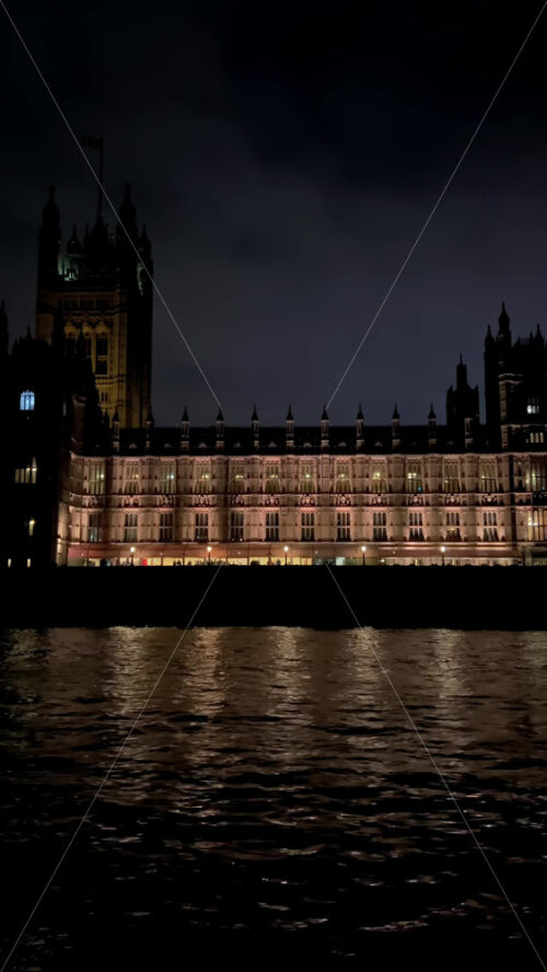 Video - View from a moving boat of the Palace of Westminster alongside the Thames River in the evening in London, England. Vertical