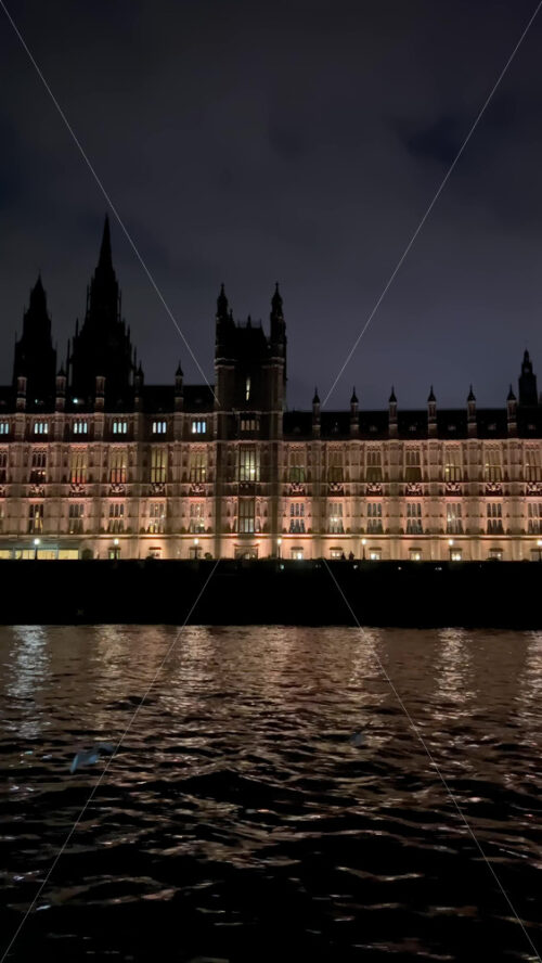 Video - View from a moving boat of the Palace of Westminster alongside the Thames River in the evening in London, England. Vertical