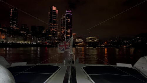Video - The flag of the United Kingdom waving on a boat moving on the Thames River in the evening in London, England