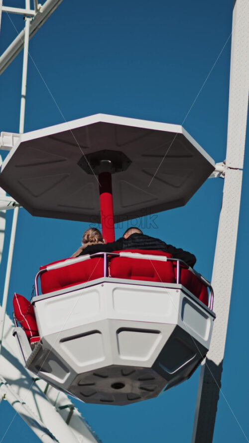 Video - Close up of people in a cabin in a Ferris Wheel with the blue sky on the background. Vertical
