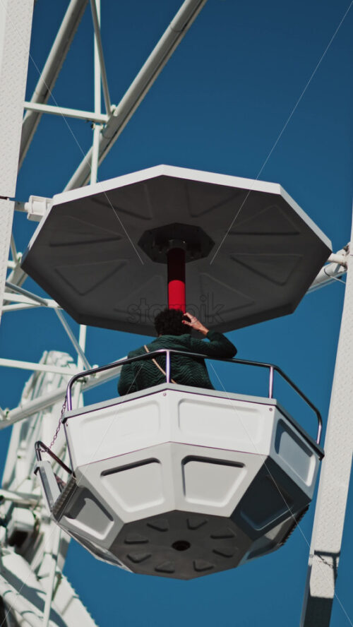 Video - Close up of people in a cabin in a Ferris Wheel with the blue sky on the background. Vertical