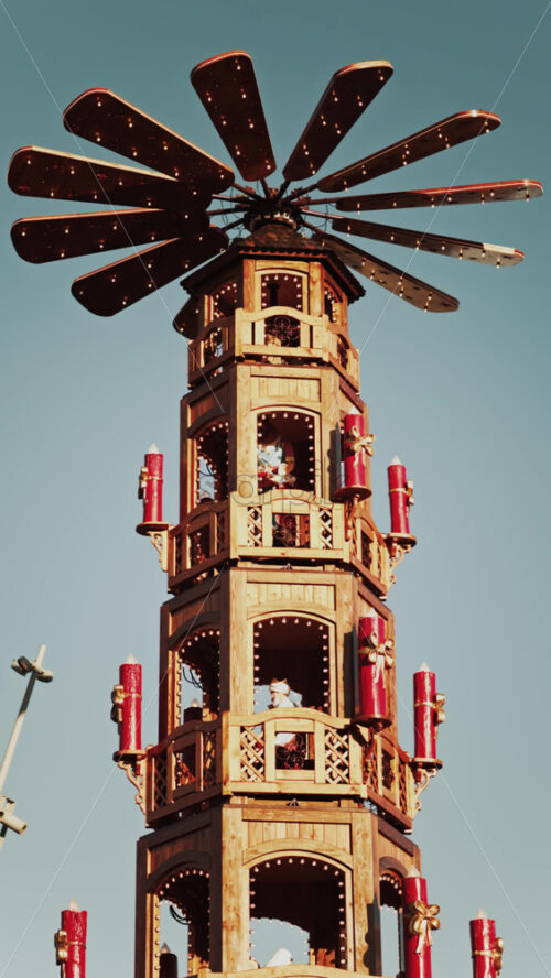Video - Traditional wooden Christmas pyramid against a clear blue sky with levels representing nativity scenes at a Christmas market in France. Vertical