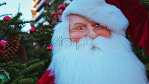 Video - Close up of a Santa Clause figurine near multiple Christmas trees