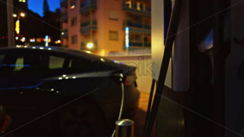 Video - Close up of an illuminated, electric car charging station at night