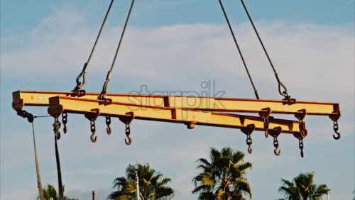 Video - A crane machine moving around with the blue sky and palm trees on the background