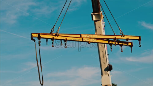 Video - A crane machine moving around with the blue sky and palm trees on the background