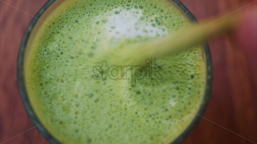 Video - Close up of a woman mixing a matcha latte with a paper straw at a cafe
