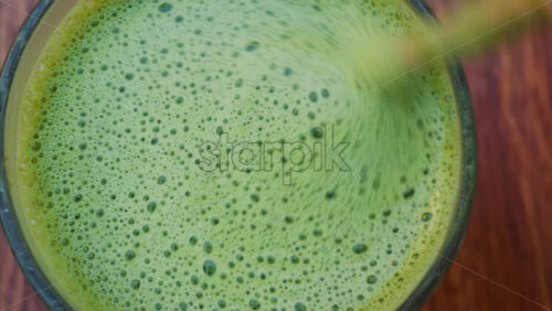 Video - Close up of a woman mixing a matcha latte with a paper straw at a cafe