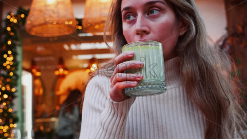 Video - Close up of a woman drinking a matcha latte with a paper straw at a cafe