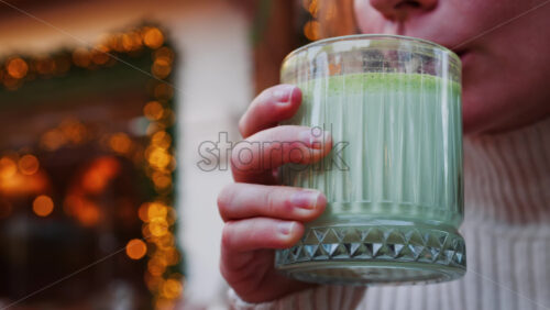 Video - Close up of a woman drinking a matcha latte with a paper straw at a cafe