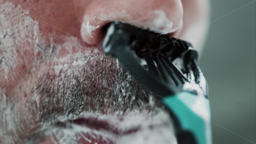 Video - Close up of a man shaving his beard with a razor