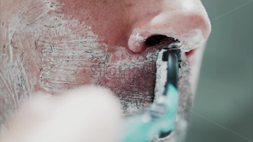 Video - Close up of a man shaving his beard with a razor