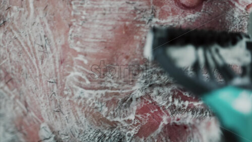 Video - Close up of a man shaving his beard with a razor