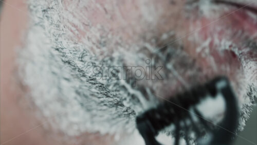Video - Close up of a man shaving his beard with a razor
