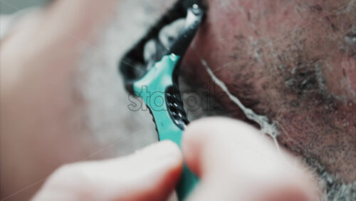 Video - Close up of a man shaving his beard with a razor
