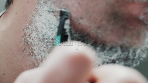 Video - Close up of a man shaving his beard with a razor