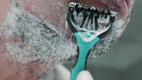 Video - Close up of a man shaving his beard with a razor