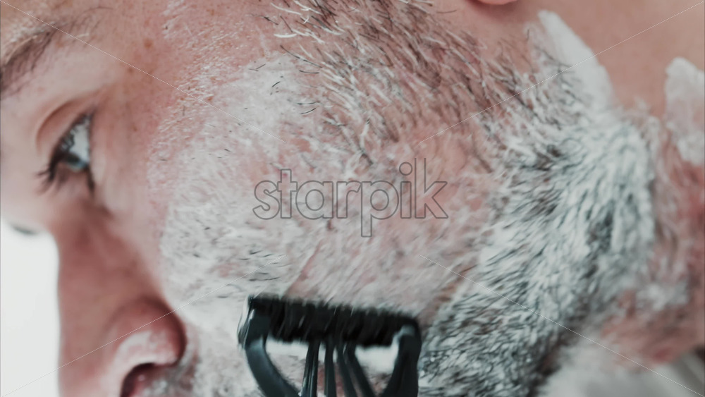Video - Close up of a man shaving his beard with a razor