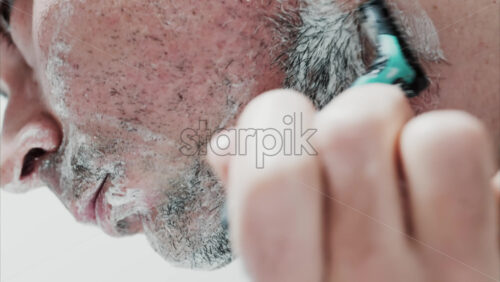 Video - Close up of a man shaving his beard with a razor