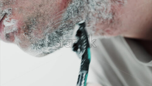 Video - Close up of a man shaving his beard with a razor
