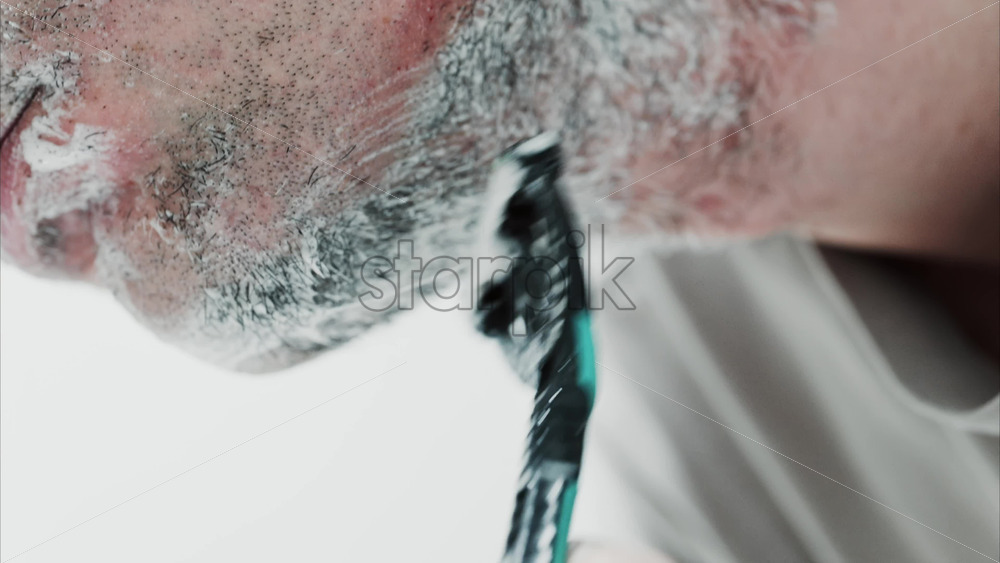Video - Close up of a man shaving his beard with a razor