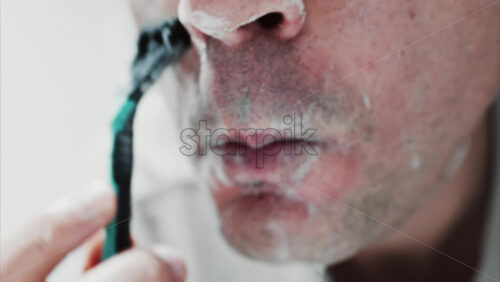 Video - Close up of a man shaving his beard with a razor