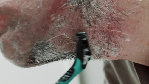 Video - Close up of a man shaving his beard with a razor
