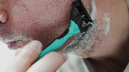 Video - Close up of a man shaving his beard with a razor