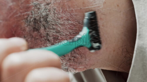 Video - Close up of a man shaving his beard with a razor