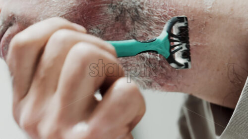 Video - Close up of a man shaving his beard with a razor