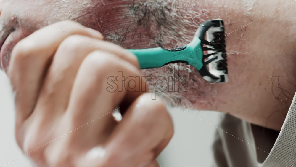 Video - Close up of a man shaving his beard with a razor
