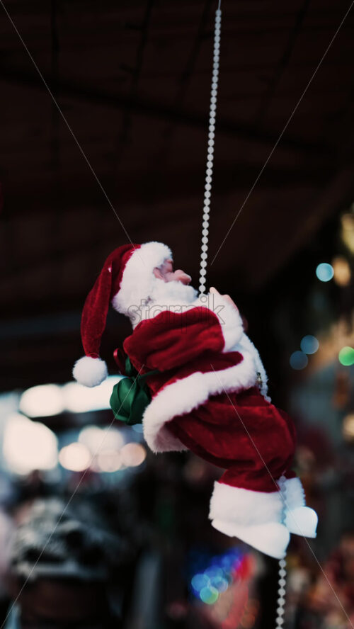 Video - Santa Claus toy moving up and down a cord with a blurry background. Vertical