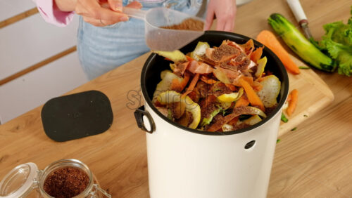 Video - Woman recycling organic waste by pouring Bokashi bran on the vegetable peels. in the kitchen