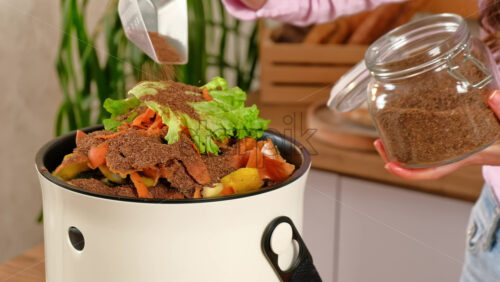 Video - Woman recycling organic waste by pouring Bokashi bran on the vegetable peels. in the kitchen