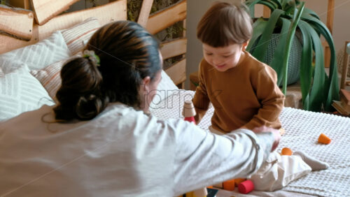 Video - Man playing with child with colourful wooden toys on the bed
