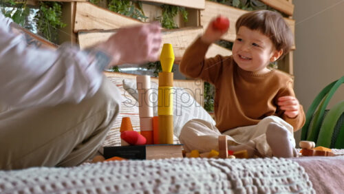 Video - Man playing with child with colourful wooden toys on the bed