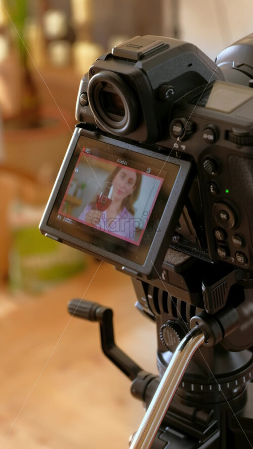 Video - Camera filming a woman drinking a glass of wine and dancing in the kitchen. Vertical