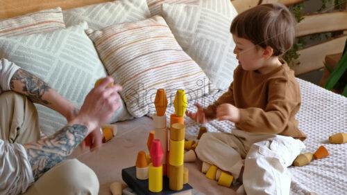 Video - Man playing with child with colourful wooden toys on the bed