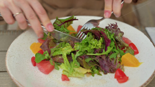 Video - Woman in brown coat eating a salad at a terrace