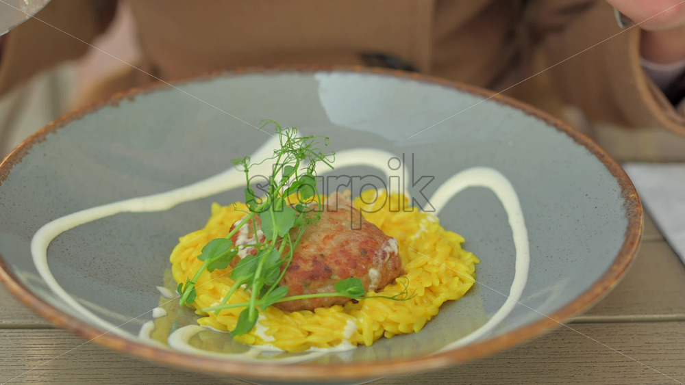 Video - Woman in brown coat eating rice with meatball at a terrace