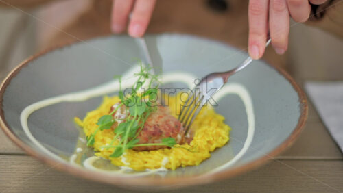 Video - Woman in brown coat eating rice with meatball at a terrace