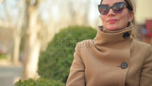 Video - Brunette woman in brown coat sitting at a terrace