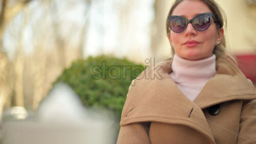 Video - Brunette woman in brown coat sitting at a terrace