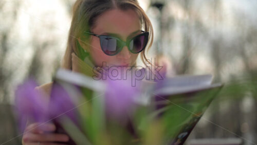 Video - Brunette woman in brown coat reading a book at a terrace