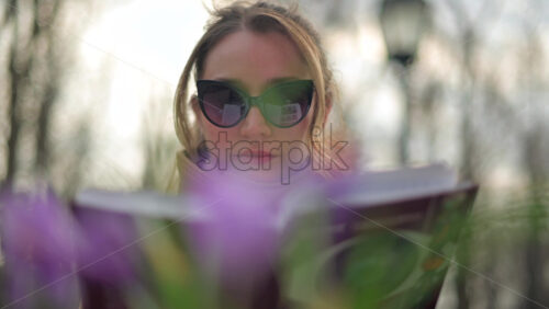 Video - Brunette woman in brown coat reading a book at a terrace