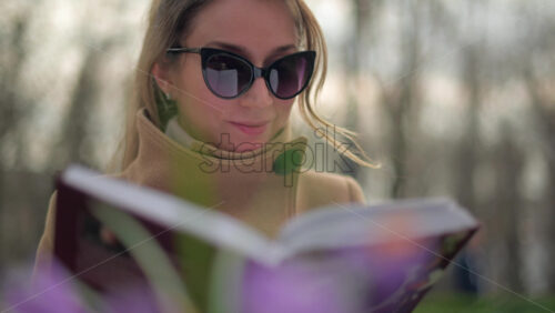 Video - Brunette woman in brown coat reading a book at a terrace