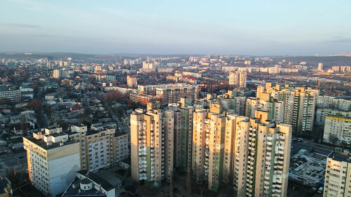 Video - CHISINAU, MOLDOVA - JANUARY 17, 2021: Aerial drone view of city at sunset. Multiple residential buildings. Bare trees, winter