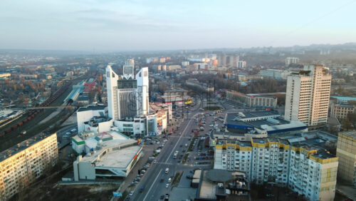 Video - CHISINAU, MOLDOVA - JANUARY 17, 2021: Aerial drone view of city at sunset. Multiple residential and commercial buildings, roads with multiple cars, railroad. Bare trees, winter