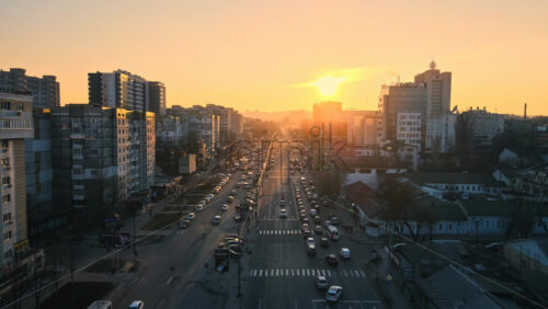 Video - CHISINAU, MOLDOVA - JANUARY 17, 2021: Aerial drone view of city at sunset. Multiple residential and commercial buildings, roads with multiple cars, walking people. Bare trees, winter
