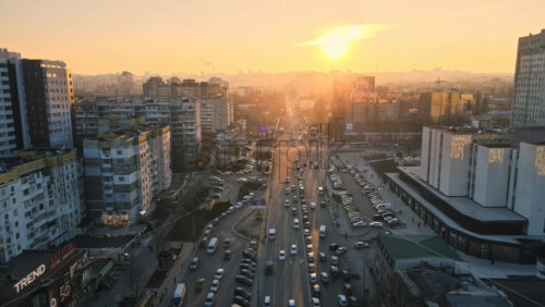 Video - CHISINAU, MOLDOVA - JANUARY 17, 2021: Aerial drone view of city at sunset. Multiple residential and commercial buildings, roads with multiple cars, walking people. Bare trees, winter